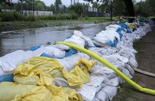 extrem väder - en linje av sand påsar och slangar till pump vatten ut av översvämmad källare i Düsseldorf, Tyskland foto