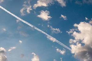 skön fluffig clouds i de morgon- med vit contrail spår av de plan flygande i de blå himmel, de spår av de flygplan i de moln, himmel, bakgrund. foto