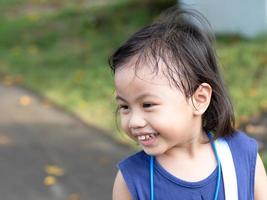 positiv charmig 4 år gammal söt asiatisk tjej, litet förskolebarn som ler och tittar åt vänster foto