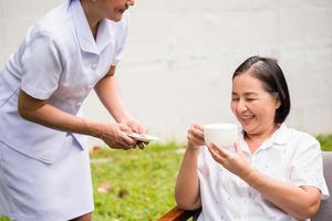 asiatisk sjuksköterska tar vård av kvinna patient på de sjukhus parkera foto