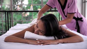 de massage terapeut masse på de tillbaka av ung asiatisk kvinna med arom grundläggande olja hudvård på spa salong. foto