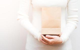 stänga upp kvinna innehar i hand brun klar tömma tom hantverk eco papper väska på vit bakgrund. foto