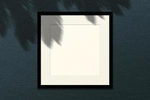 minimal tömma fyrkant vit ram bild falsk upp hängande på vägg bakgrund med löv fönster. foto
