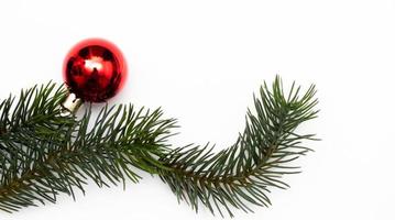 topp se av jul gåva låda röd bollar med gran grenar, tall kottar, röd bär och klocka på vit bakgrund. foto