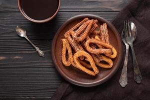 hemlagad churros med choklad på en mörk trä rustik bakgrund. foto