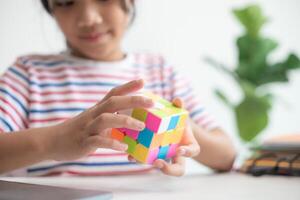 asiatisk liten söt flicka innehav rubiks kub i henne händer. rubiks kub är en spel den där ökar de intelligens av barn. foto