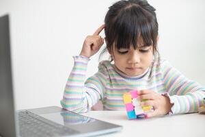 asiatisk liten söt flicka innehav rubiks kub i henne händer. rubiks kub är en spel den där ökar de intelligens av barn. foto