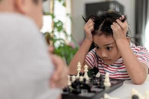 liten pojke och liten flicka spelar schack hemma. barn spelar schack foto