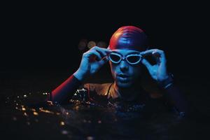 äkta triathlete simmare har en ha sönder under hård Träning på natt neon gel ljus foto