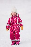 liten flicka har roligt på snöig vinter- dag foto