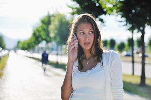 ung kvinna prata förbi mobiltelefon på gata foto