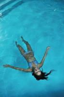 Söt ung lady avkopplande i de simning slå samman foto