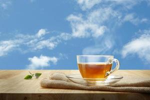 te kopp med och te blad säckväv på de trä- tabell och de himmel bakgrund foto
