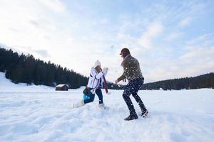 Lycklig familj spelar tillsammans i snö på vinter- foto