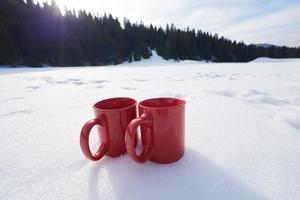 två röd kupper av varm te dryck i snö på vinter- foto