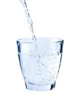häller färsk ren vatten in i en glas isolerat på vit bakgrund, sjukvård och skönhet hydratisering begrepp foto