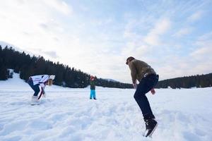 Lycklig familj spelar tillsammans i snö på vinter- foto