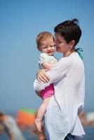 mamma och bebis på stranden har kul foto