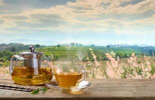 te kopp och glas kannor eller burkar. med och te blad säckväv på de trä- tabell och de te plantager bakgrund foto