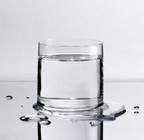 glas av ren vatten med vatten droppar på tabell, sjukvård och skönhet hydratisering begrepp foto