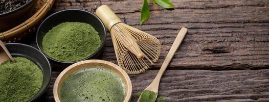 japansk organisk matcha grön te pulver i skål med tråd vispa och grön te blad på trä- bakgrund, organisk produkt från de natur för friska med traditionell stil foto