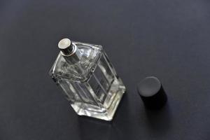 en glas flaska med parfym på en svart bakgrund. en skön flaska med en parfym spray dispenser. foto