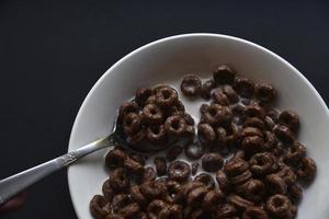 utsökt choklad majs ringar i mjölk i en kopp. utsökt frukost av flingor och mjölk. foto