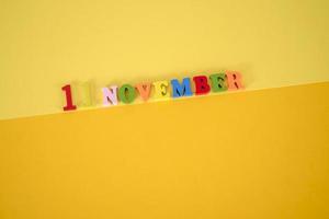 november 11 på en gul, papper bakgrund med trä- och flerfärgad brev med Plats för text. foto