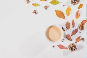 höstens sammansättning. kopp kaffe, höstlöv, kanelstänger och anistjärnor på klarblå pastellbakgrund. platt låg, ovanifrån kopia utrymme. foto