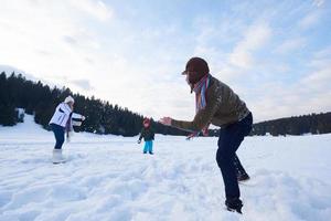 Lycklig familj spelar tillsammans i snö på vinter- foto