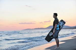 porträtt av en ung kitsurf man på strand på solnedgång foto