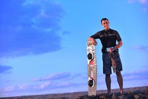 porträtt av en ung kitsurf man på strand på solnedgång foto