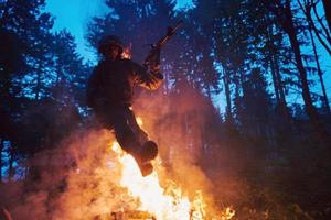 soldat i verkan på natt Hoppar över brand foto