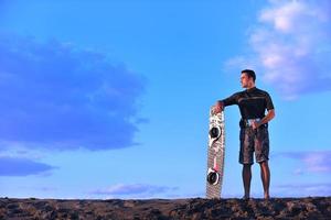 porträtt av en ung kitsurf man på strand på solnedgång foto