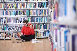 de studenter användningar en anteckningsbok, bärbar dator och en skola bibliotek foto