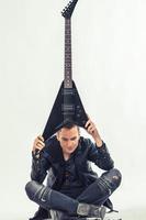 tung metall musiker innehav elektrisk gitarr ovan hans huvud. foto