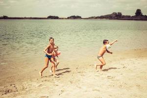Lycklig Pojkar har roligt på de strand i sommar dag. foto