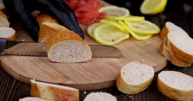 skär färsk vetebaguette i bitar under tillagningen foto