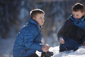 barn spelar med färsk snö foto