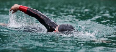 triathlon idrottare simmar på sjön bär våtdräkt foto