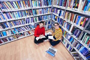 de studenter användningar en anteckningsbok, bärbar dator och en skola bibliotek foto