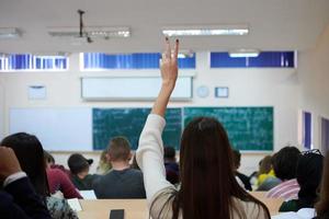 kvinna studerande Sammanträde i de klass och höjning hand upp foto