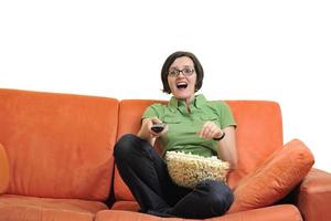 ung kvinna äta popcorn och tittar på TV foto
