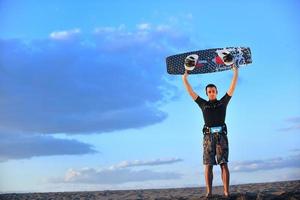 porträtt av en ung kitsurf man på strand på solnedgång foto