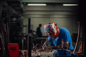 professionell tungindustrisvetsare som arbetar inne i fabriken, bär hjälm och börjar svetsa. selektiv fokusering foto