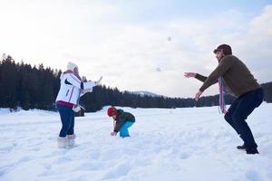 Lycklig familj spelar tillsammans i snö på vinter- foto