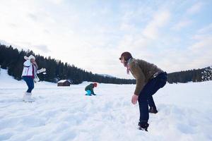 Lycklig familj spelar tillsammans i snö på vinter- foto