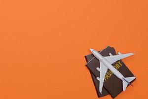 kreativ flatlay av resenärer Tillbehör med pass och flygplan leksak isolerat orange bakgrund med tömma rymd, tropiskt resa begrepp foto