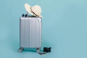 resa bagage med pass, kamera, hatt och solglasögon isolerat på blå bakgrund med kopia Plats, resa begrepp bakgrund foto