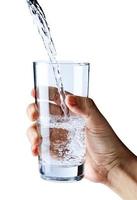 häller vatten in i glas i hand isolerat på vit bakgrund, sjukvård och skönhet hydratisering begrepp foto